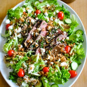 A salad with meat and vegetables on top of it.