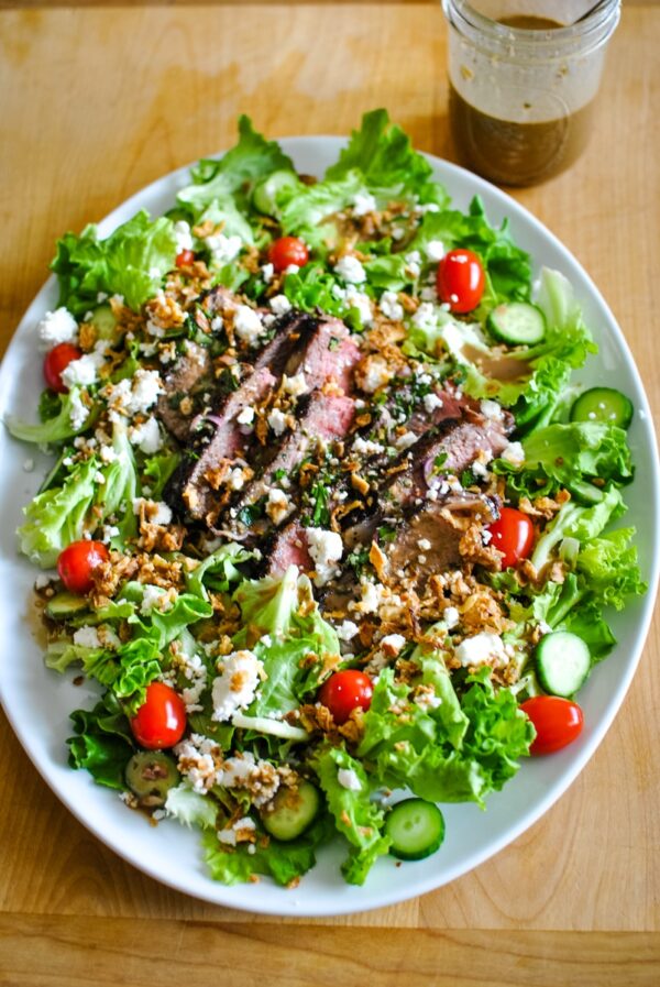 A salad with meat and vegetables on top of it.