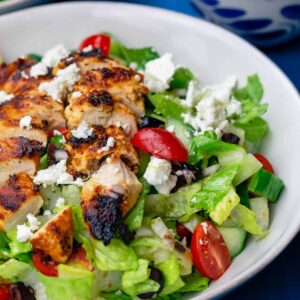 A salad with chicken and feta cheese in it.