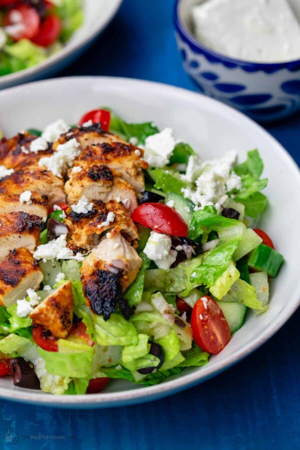 A salad with chicken and feta cheese in it.