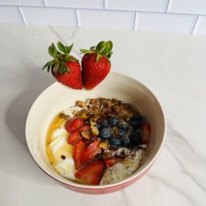 A bowl of food with fruit and nuts on top.