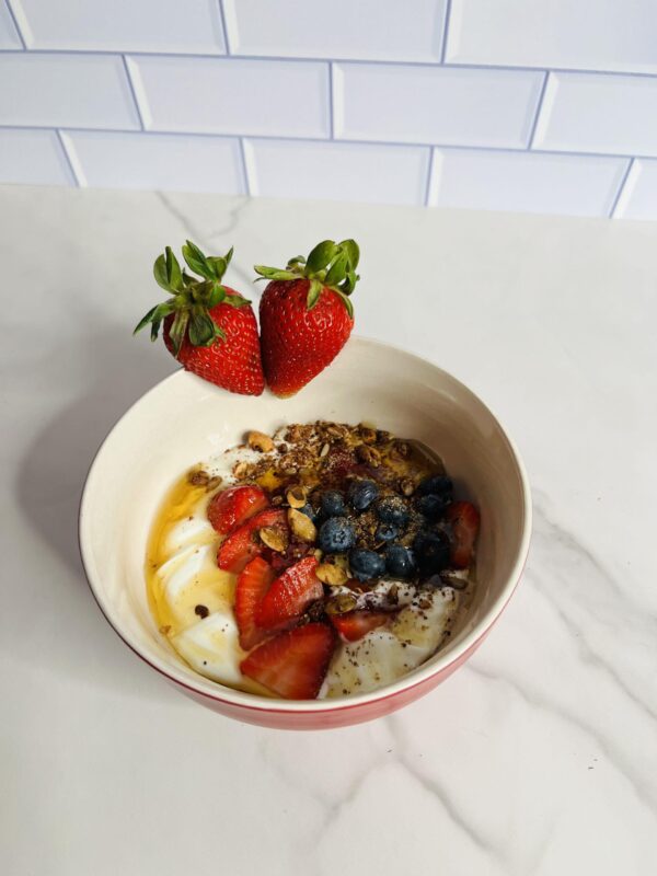 A bowl of food with fruit and nuts on top.