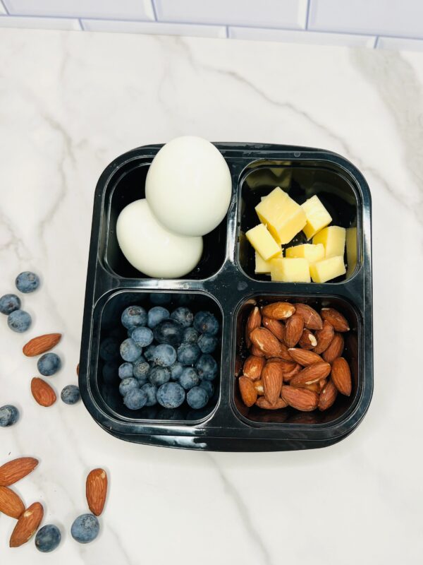 A black tray with eggs, blueberries and almonds.