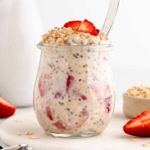 A jar of oatmeal with strawberries on top.