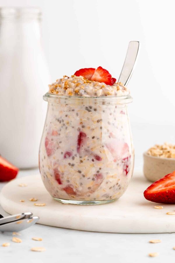 A jar of oatmeal with strawberries on top.