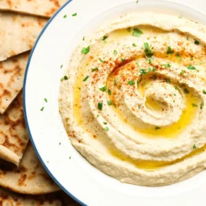 A plate of hummus and pita bread on the side.