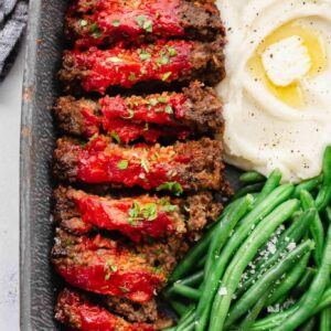 A plate of meat and vegetables with sauce.