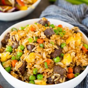 A bowl of rice and meat with peas.