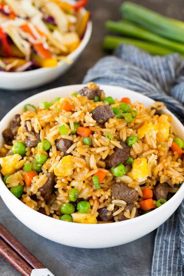 A bowl of rice and meat with peas.