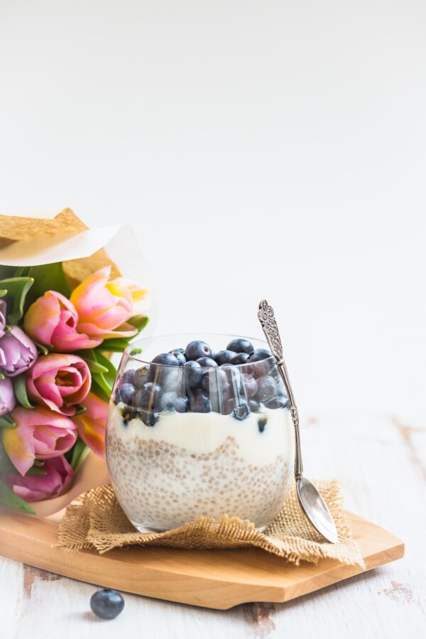 A bowl of food with blueberries and cream on top.