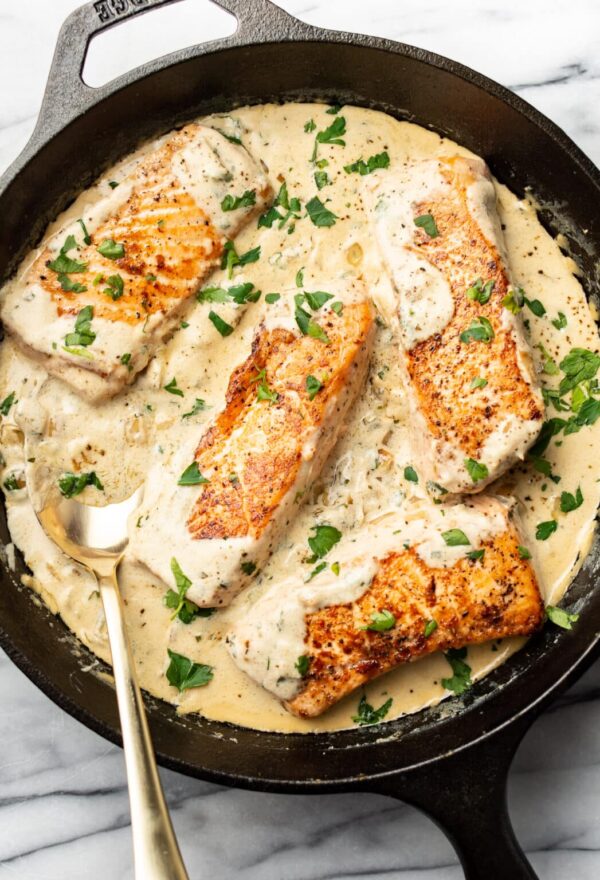 A pan of fish with sauce and parsley.