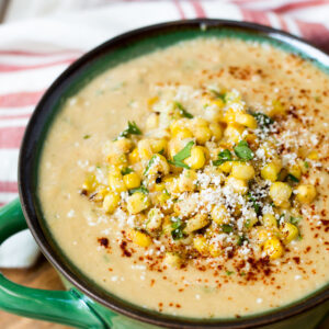 A bowl of corn chowder with cheese and herbs.