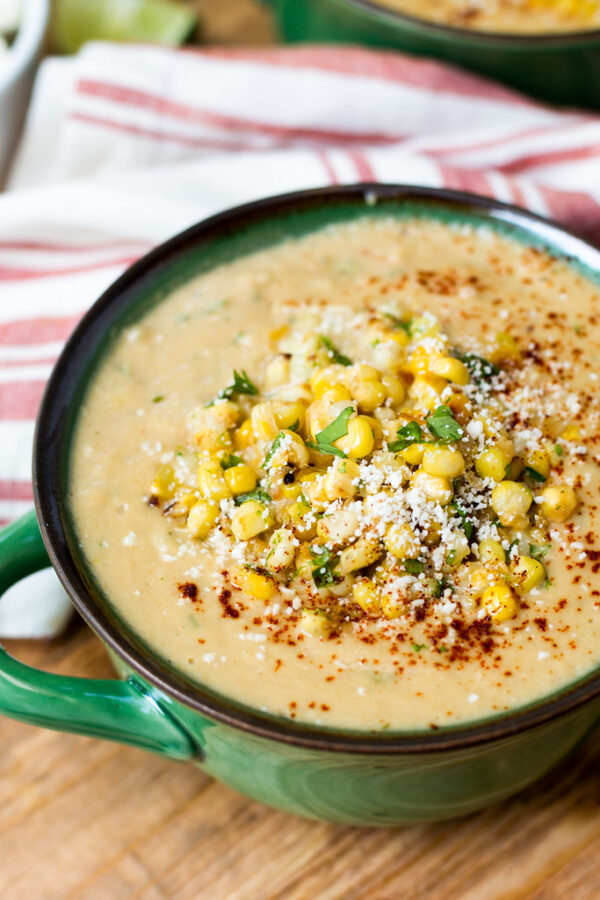 A bowl of corn chowder with cheese and herbs.