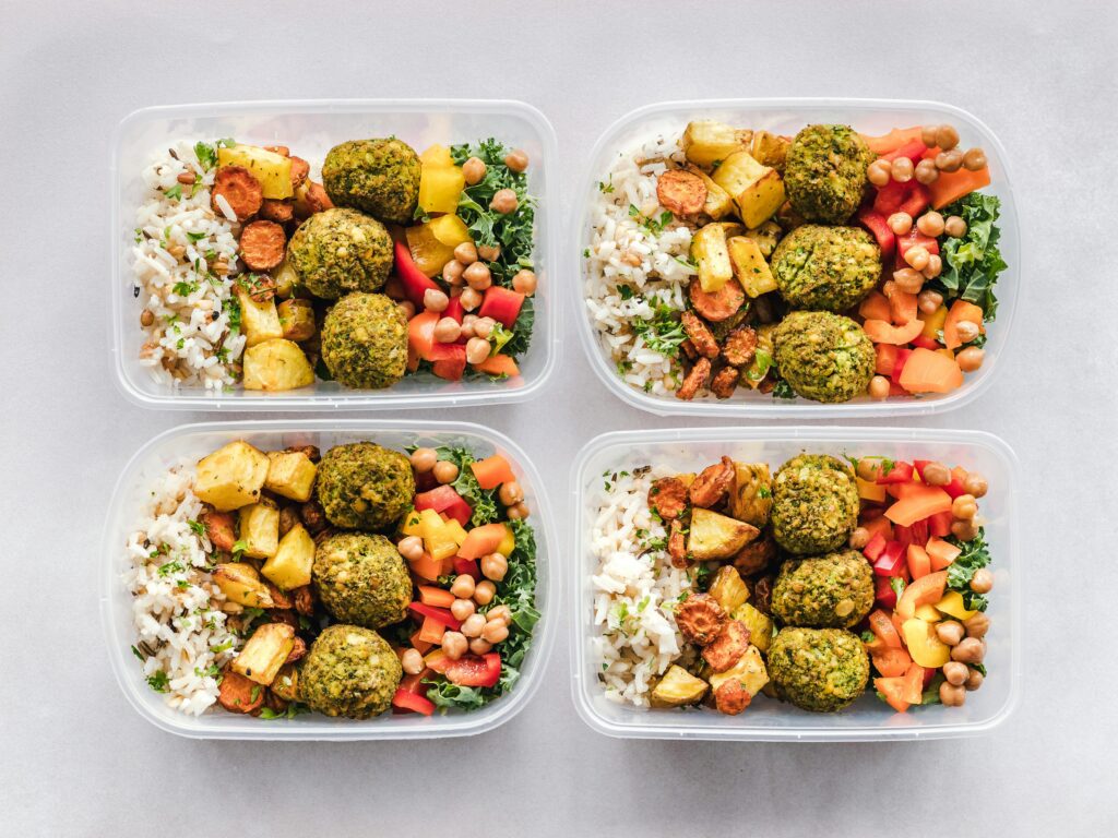 Four containers of food with different types of vegetables.