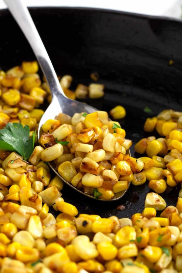 A spoon full of corn on the cob with seasoning.