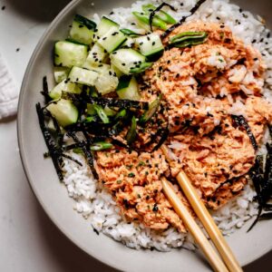 A bowl of rice and vegetables with chopsticks.