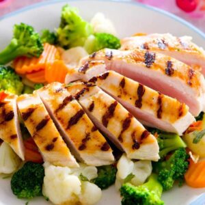 A plate of food with chicken, broccoli and carrots.