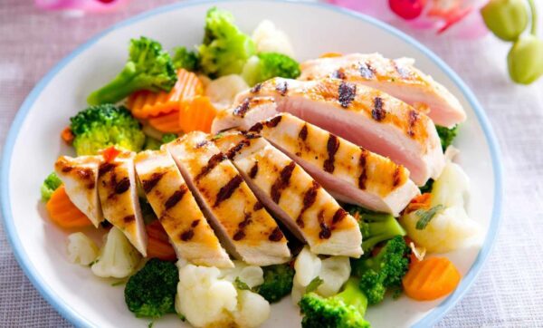 A plate of food with chicken, broccoli and carrots.