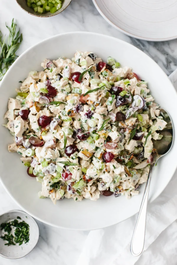 A bowl of salad with grapes and nuts.